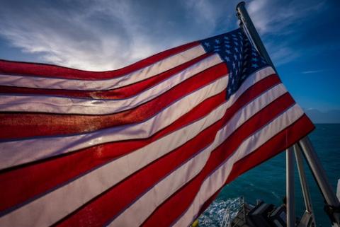 american flag flying in wind from boat on ocean